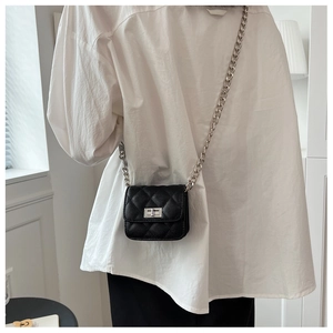 Detail view of mini black quilted crossbody bag with silver chain strap and twist lock