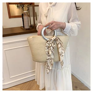 Detail of woven straw tote bag with silver metal ring handle and decorative silk scarf