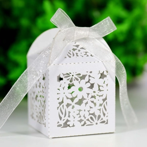 Detail of laser-cut floral paper gift box with elegant white ribbon and intricate patterns