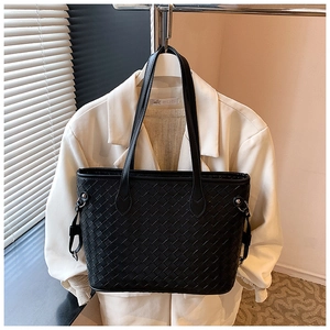 Detailed close-up of the black woven leather tote bag with elegant shoulder straps