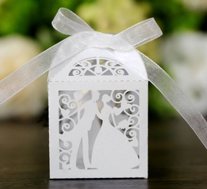 Detailed laser-cut white wedding favor box with bride and groom silhouette and ribbon