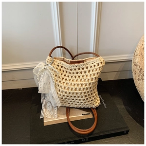 Détail du sac en paille crocheté avec lanières en cuir et nœud décoratif en dentelle