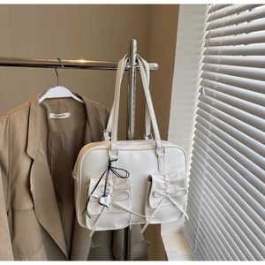 Dettaglio dello zaino beige in stile balletto con fiocco e ciondolo a cuore in metallo