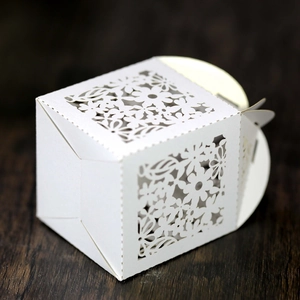 Detailed close-up of white laser-cut wedding favor box with intricate floral hollow patterns