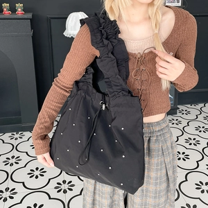 Detail of black nylon tote bag featuring ruffled shoulder strap and white polka dot accents