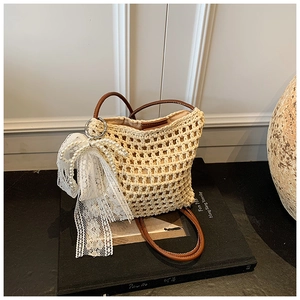 Détail d'un sac à bandoulière tissé beige avec nœud en dentelle et perles
