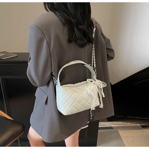 Quilted light mint green crossbody bag with pearl bow charm worn by a model