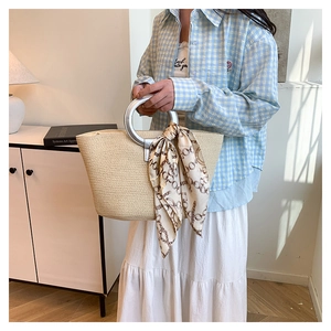 Detail view of woven beach tote with silver ring handles and silk scarf accent