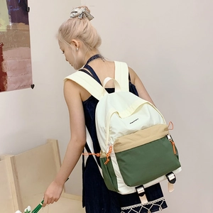 Detail of color-block nylon backpack featuring cream, khaki, and dark green segments