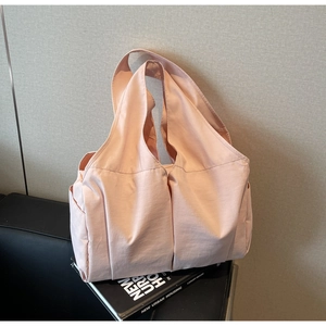 Detail view of pink multi-pocket tote bag with wide shoulder strap on minimal books