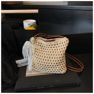 Détail du sac bandoulière au crochet beige avec nœud, perles et sangle en cuir brun