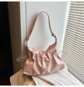 Détail du sac plissé rose en cuir brillant avec bandoulière réglable et design chic