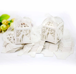 Laser-cut white wedding favor boxes with groom and bride silhouettes and white ribbon
