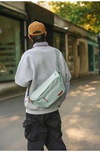 Détail du sac bandoulière vert menthe en nylon résistant avec écusson en cuir sur le devant