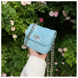 Close-up of light blue quilted mini bag with silver chain strap and metal clasp detail