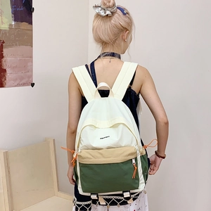 Three-color nylon backpack in beige and green worn by a model in a natural setting