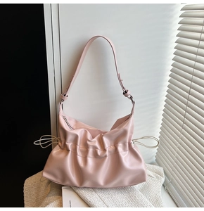 Détail d'un sac à bandoulière en cuir verni rose clair avec texture froncée et cordon