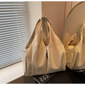 Vue détaillée d'un sac cabas plissé beige avec poches latérales à cordon fonctionnelles