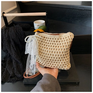 Détail du sac bandoulière tressé crème avec nœud en dentelle et perles élégantes