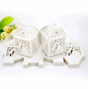 Detail of laser-cut white wedding favor boxes featuring bride and groom silhouette design