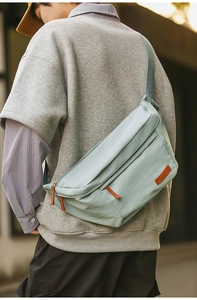 Détail du sac de poitrine bleu clair montrant le logo en cuir et la bandoulière