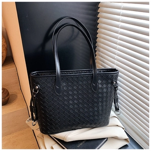 Detailed view of black woven leather tote bag featuring a silver metal ring attachment