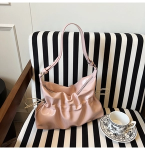 Détail du sac à bandoulière en cuir verni rose avec plis et cordons latéraux