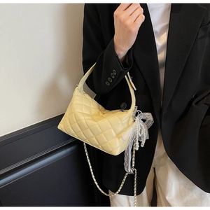 Detail of quilted leather pillow bag with lace bow and pearl charm strap on woman