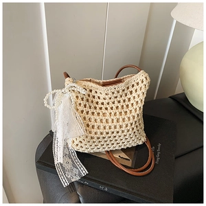 Détail du sac bandoulière beige tissé avec texture crochet et décoration de nœud en dentelle