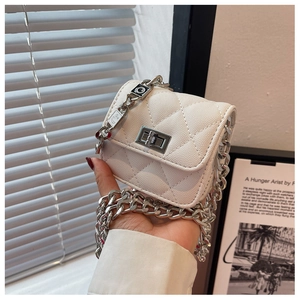 Detailed close-up of white quilted leather mini bag with silver chain and metal lock