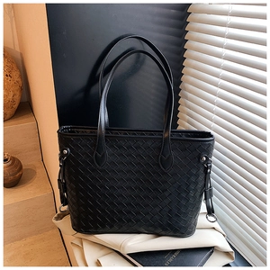Macro detail of high-quality black woven texture and leather strap on tote bag