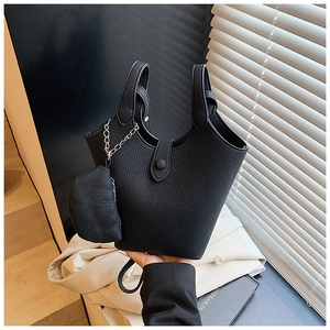 Detail view of black litchi grain bucket bag with matching chain pouch held by a model