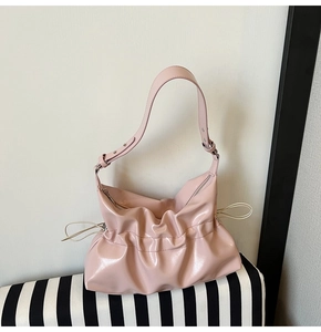 Détail du sac hobo en cuir verni rose clair avec texture plissée et cordon latéral