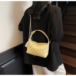 Quilted yellow leather handbag shown on model featuring a chic chain strap and pillow shape