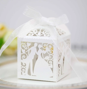 Detail of laser-cut hollow wedding candy box with bride and groom silhouette and white ribbon