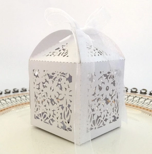 Detail of laser-cut floral patterns on white paper candy box with ribbon tie