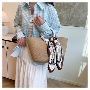 Detailed texture of the woven straw tote bag with silver ring handle and floral silk scarf