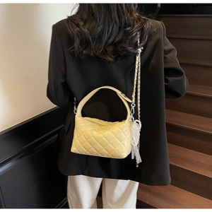 Close-up of quilted yellow crossbody bag with pearl and metal chain shoulder strap