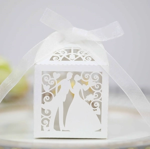 Detail of white laser cut wedding candy box with bride and groom silhouette and ribbon