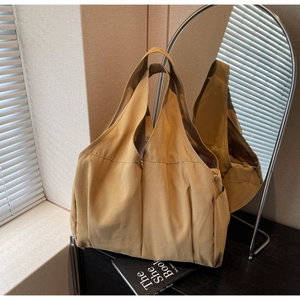 Détail du sac cabas en nylon kaki avec large bandoulière et poche latérale pratique