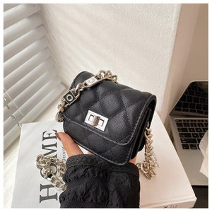 Detailed macro view of black quilted mini bag with silver chain and litchi texture
