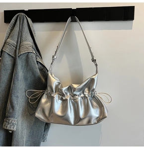 Sac à bandoulière argenté métallisé plissé suspendu à côté d'une veste en jean