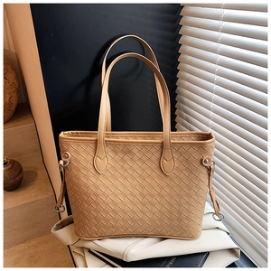 Detail of woven light brown leather tote bag with metallic D-ring and handle texture