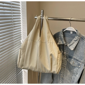 Détail du cabas en toile beige avec ouverture en V et poche latérale sur support métal