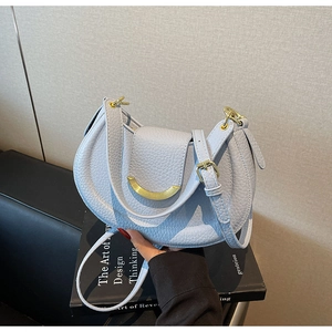 Close-up of light blue saddle bag with lychee grain leather and gold metal buckle detail