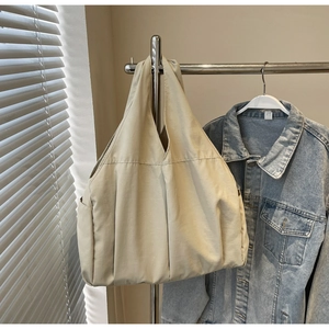 Détail d'un grand sac fourre-tout beige suspendu avec une veste en jean en arrière-plan