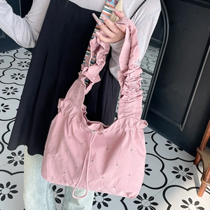 Detail of pink nylon tote bag with pleated handles and rhinestone accents on a shoulder