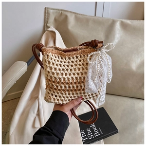 Détail du sac à bandoulière tissé main avec dentelle délicate et breloque nœud perle