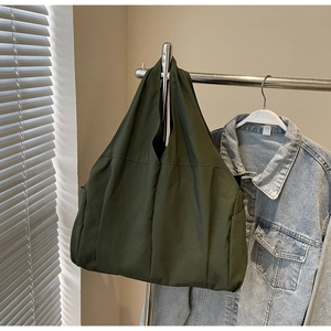 Gros plan du sac fourre-tout en nylon vert olive suspendu avec une veste en jean décontractée