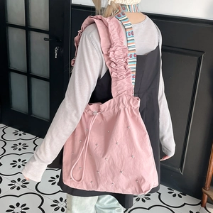 Detail of pink nylon tote bag featuring silver beads and decorative ruffled strap